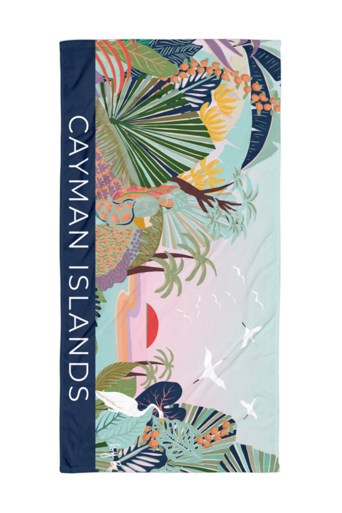A beach towel featuring a colorful tropical print with palm leaves, flamingos, birds, and a pastel landscape, bordered by a navy blue side panel with the text 'CAYMAN ISLANDS' in white.